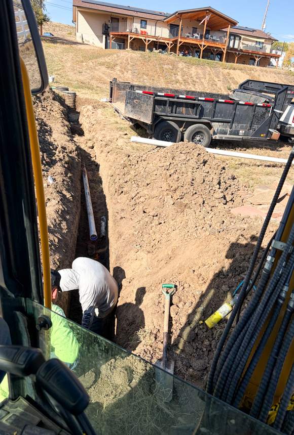 Crew member in a trench next to new PVC pipe