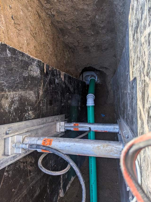 Green sewer pipe and fitting inside a shored trench