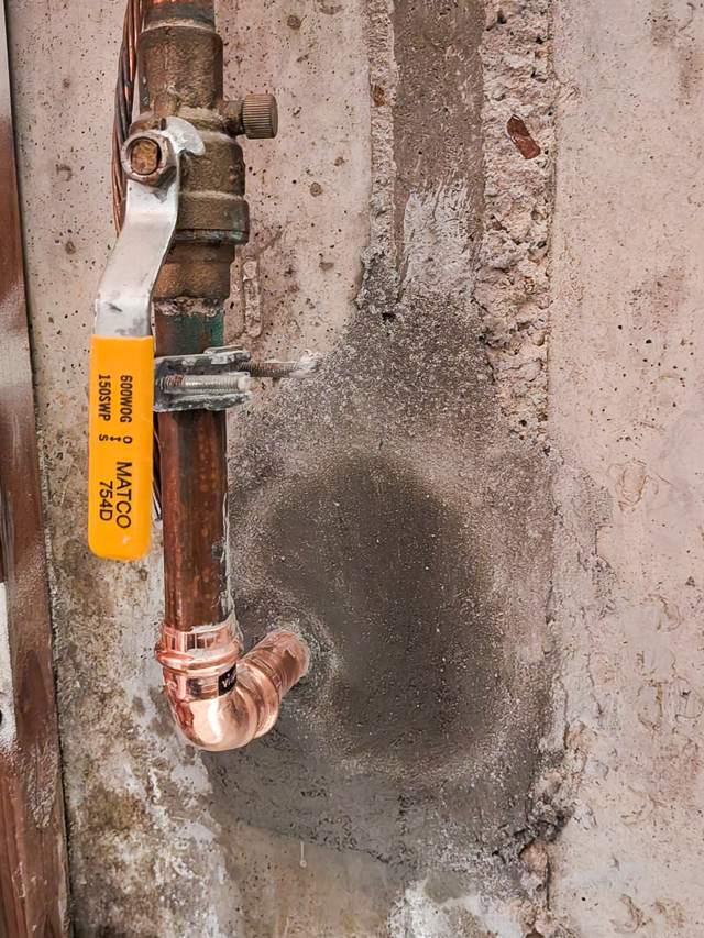 New copper elbow and ball valve on a concrete wall